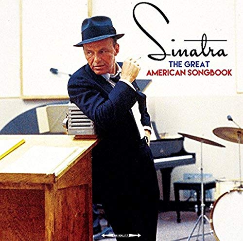Frank Sinatra in a hat and suit leaning on a piano in a studio.