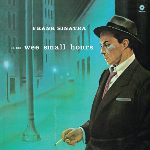 Frank Sinatra in a fedora and suit stands on a blue-toned city street.