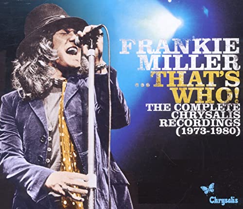 Frankie Miller singing into a microphone on stage under blue spotlight.