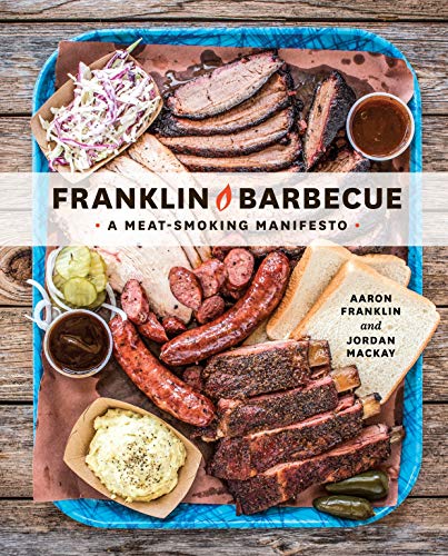 A blue tray holds a spread of sliced brisket, ribs, sausage, sides, and bread.