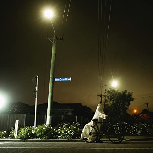 Night street scene with figure on bicycle under streetlights.