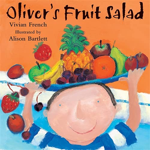 A boy balances a large platter of assorted colorful fruit on his head.