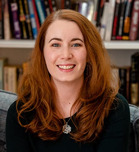 Smiling woman with red hair in front of a bookshelf.
