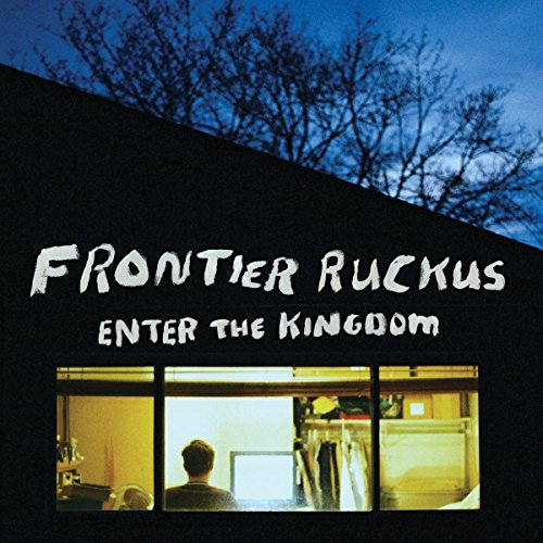 "Album cover with a man in a lit room, dark exterior, and bare trees."