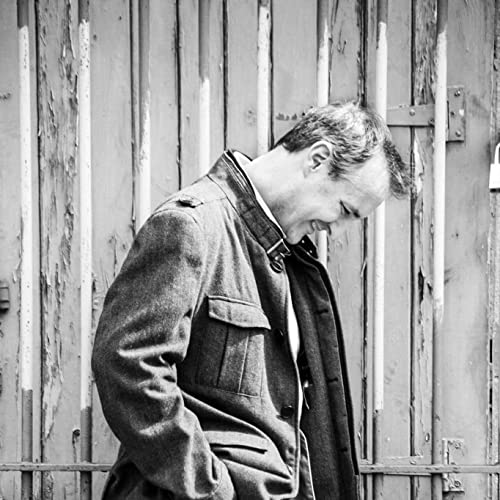 Black and white portrait of a man in a jacket, looking down.