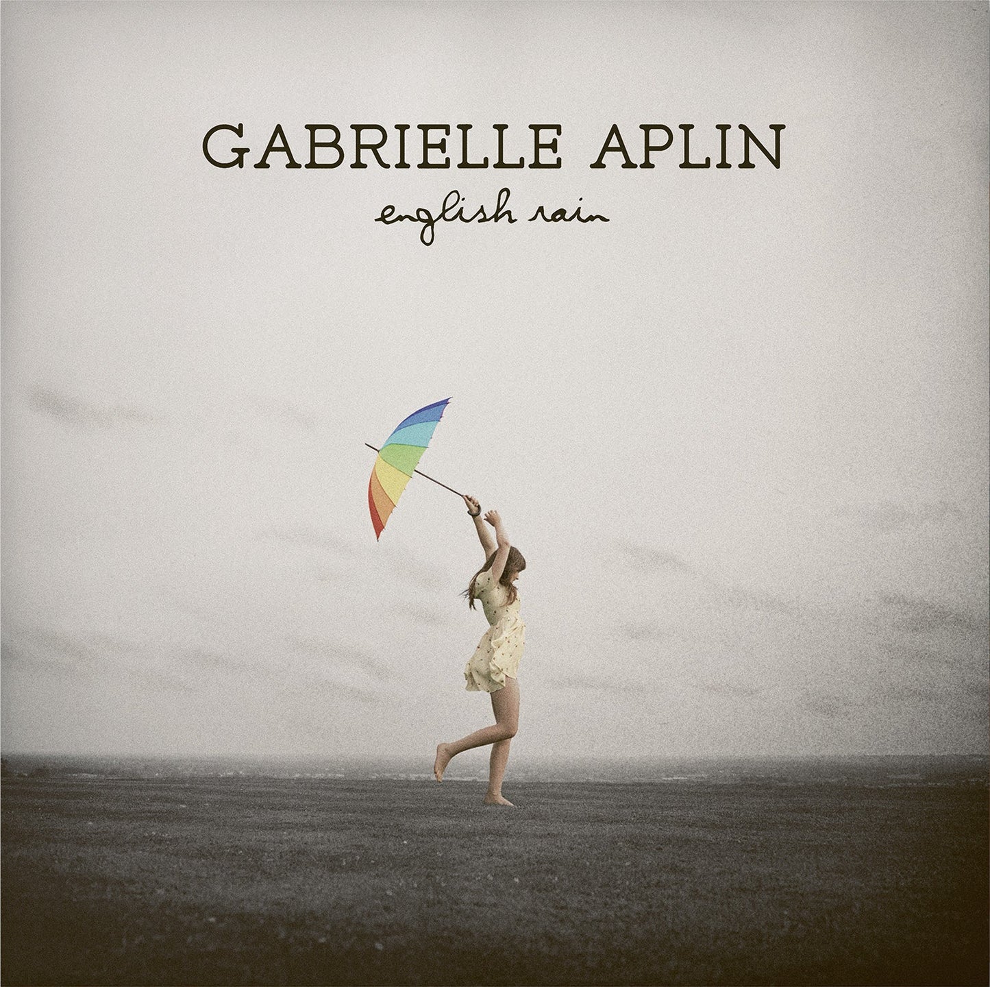 CD cover: girl with rainbow umbrella in a field, muted tones.