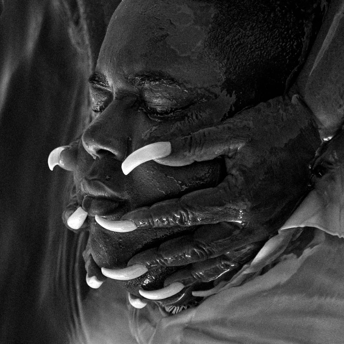 Black and white close-up portrait of a person with long, white nails.