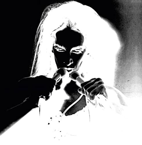 Black and white portrait of Diamanda Galas singing into a microphone.