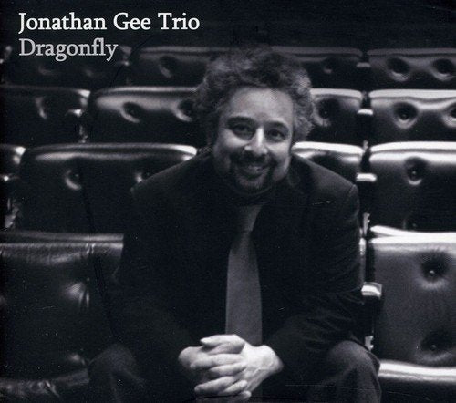 Black and white portrait of Jonathan Gee, seated in a theater.