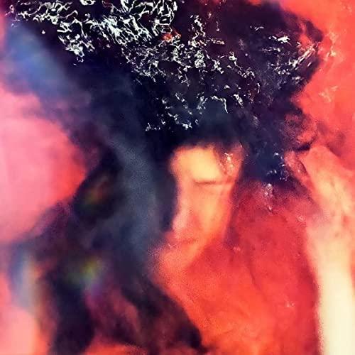 Abstract album cover with blurred face in red and dark tones.