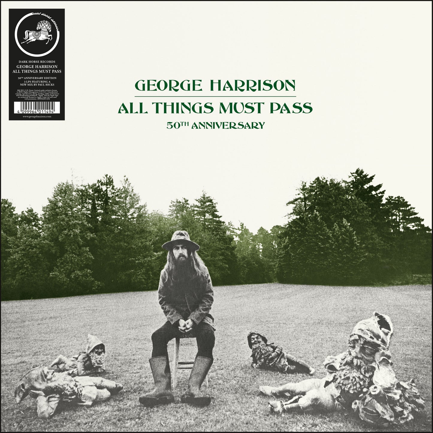 George Harrison sitting on a stool surrounded by garden gnomes in a grassy field.