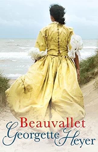 A woman in a yellow period dress walks on a sandy beach near water.