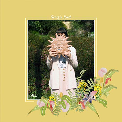 Woman holding sun-shaped mask in a garden, album cover for Georgia Ruth’s “Mai”.
