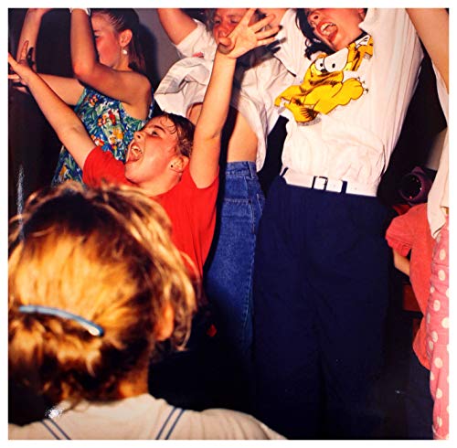 Crowd of people with arms raised, captured in a grainy, vintage photograph.