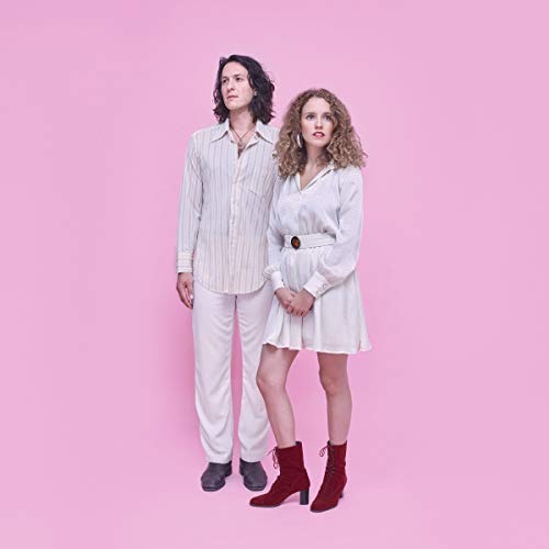 Geowulf duo posing in matching, light-colored outfits against a pink background.