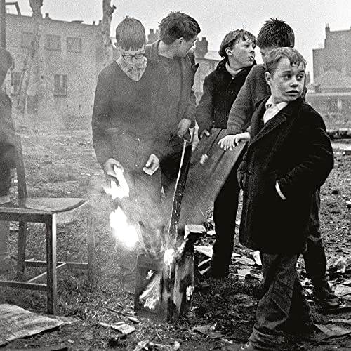 Black and white photo of four boys with a small fire.
