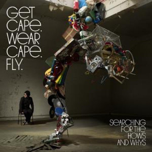 CD cover: man sitting, chaotic pile of objects, text "Get Cape. Wear Cape. Fly.