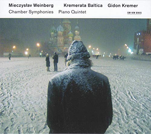 Snowy landscape with a person’s back facing ornate, illuminated buildings.