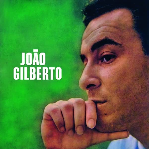 Close-up portrait of João Gilberto against a green textured background.