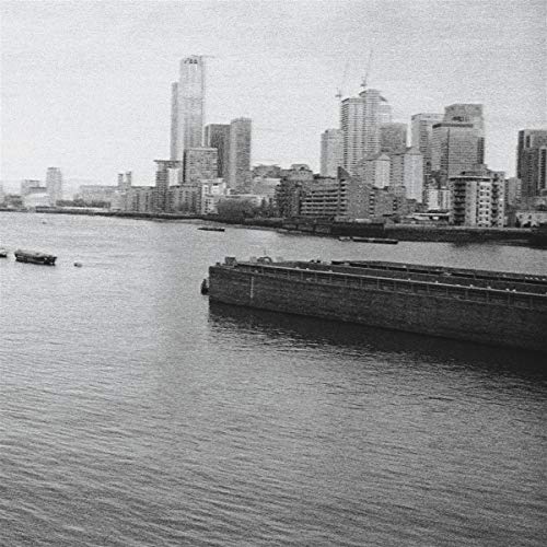 Black and white cityscape with a river and barge in foreground.