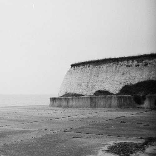 Black and white photo of a coastal cliff and concrete seawall.