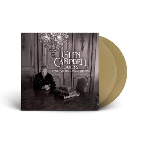 Glen Campbell sits at a table with books, next to two gold vinyl records.