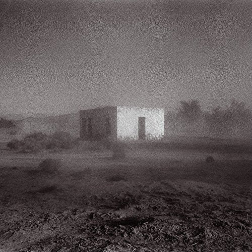 Black and white photo of a small, isolated building in a hazy landscape.