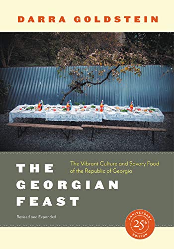 Book cover: a long table set for a feast outdoors, title text below.