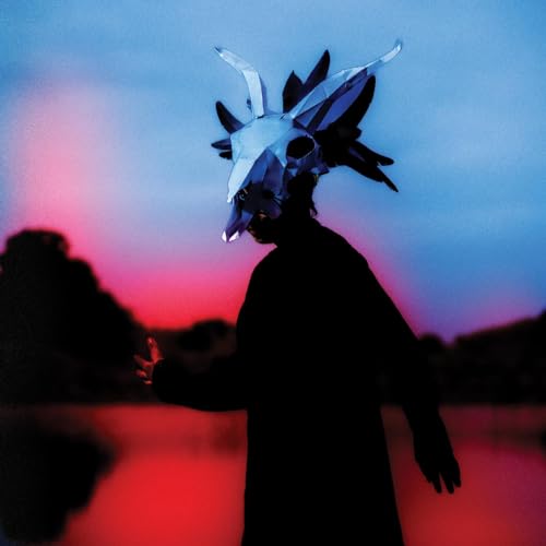 Person in animal skull mask against a vibrant blue and red sky.