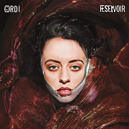 A woman's face partially submerged in dark, swirling liquid with text Gordi Reservoir above.