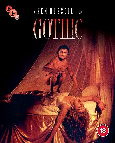 A small creature crouches on a woman lying on a bed in red lighting.