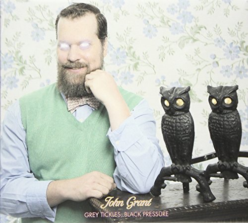 "Album cover featuring a man with owl figurines on a table."