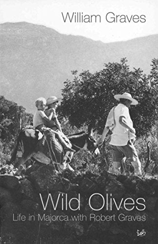 A man leads a donkey carrying two children along a stone wall in Majorca.
