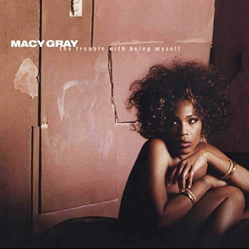 Album cover featuring a woman sitting against a worn, pink wall, with curly hair.