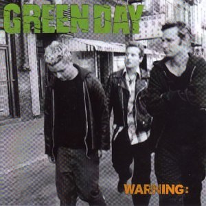 The three members of Green Day walking down a city street in black and white.
