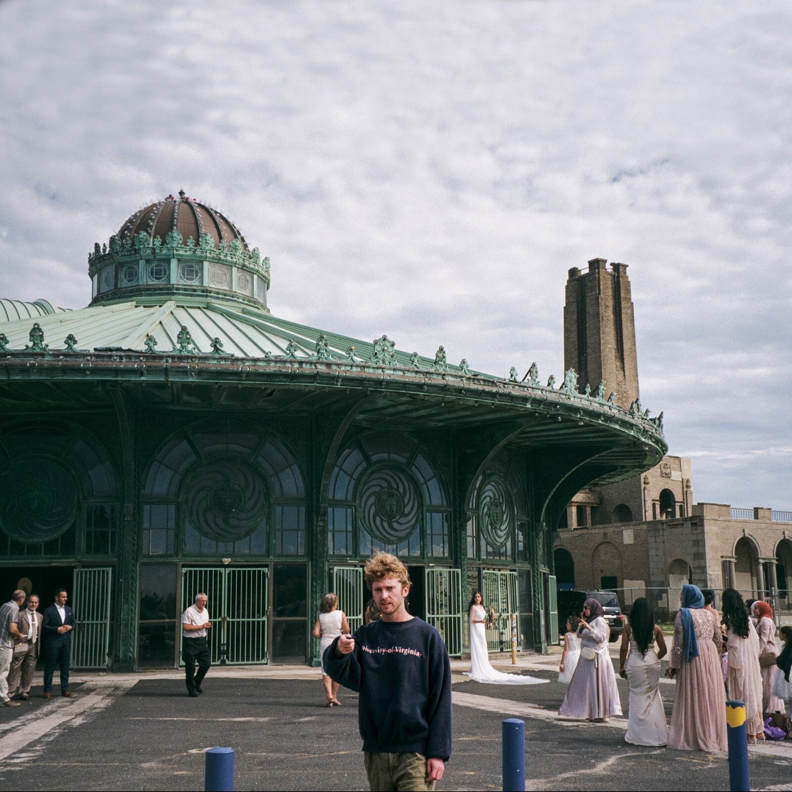 Man stands before a large, ornate green building with people nearby.