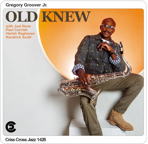Gregory Groover Jr. sits holding a saxophone against a white and orange background.