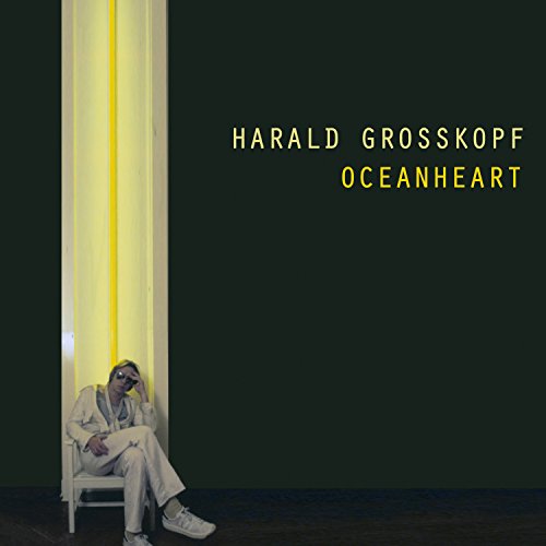 "Album cover with man sitting on a chair, wearing white, against a dark background."