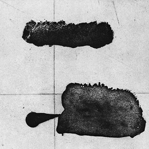 Black ink blots on a light grey tiled surface.