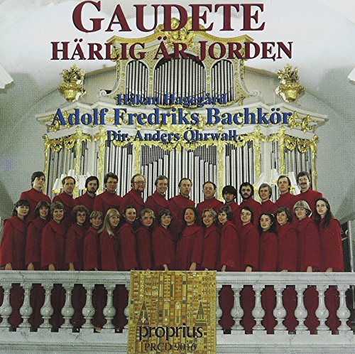 Choir in red robes posing in front of a large pipe organ.