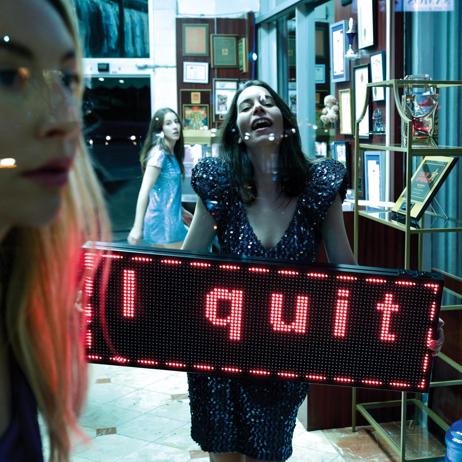 HAIM album cover: women with a red “I quit” sign, indoors.