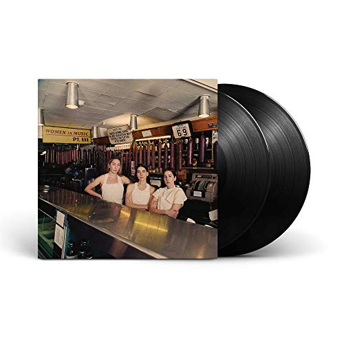 Three women standing behind a deli counter next to two black vinyl records.