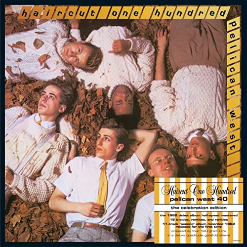 Five men in sweaters and shirts lying on a bed of dry autumn leaves.