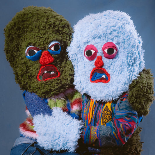 Two figures wearing fuzzy green and blue monster masks embrace against a blue background.