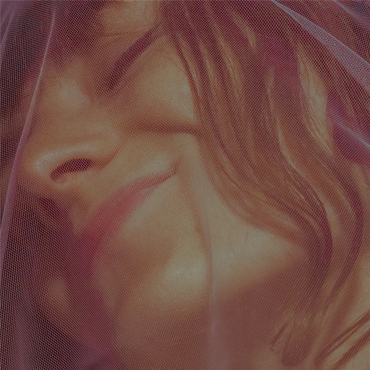 Close-up of a person’s face partially obscured by reddish mesh fabric.