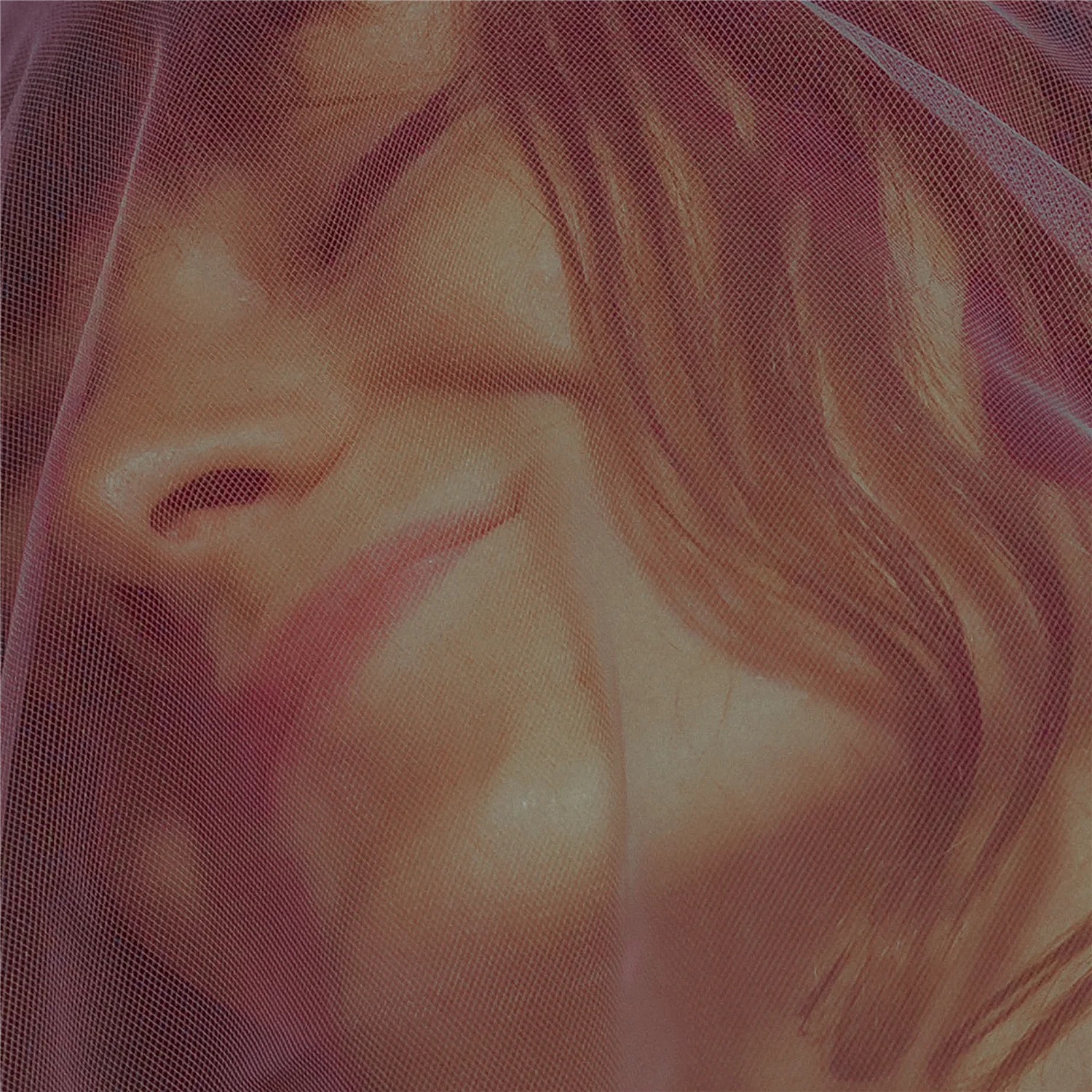 Close-up of a person’s face partially obscured by reddish mesh fabric.