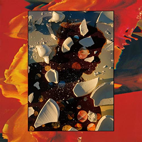 Album cover with a face obscured by shattered porcelain and orange hues.