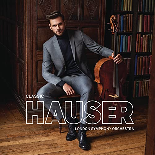 Cellist Hauser in grey suit, with cello, against a bookshelf backdrop.