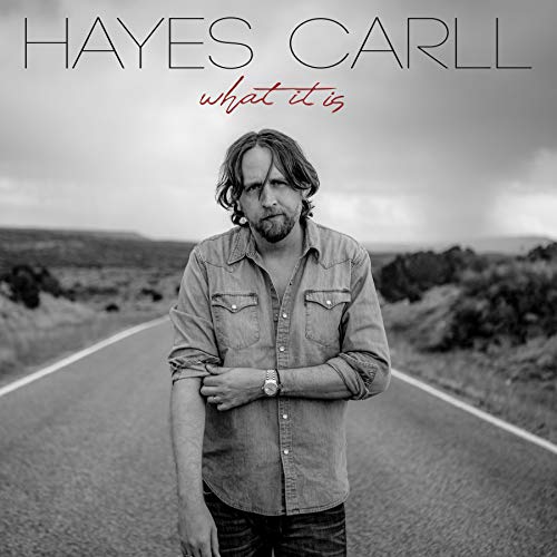 "Album cover with a man standing on a desert road, arms crossed."