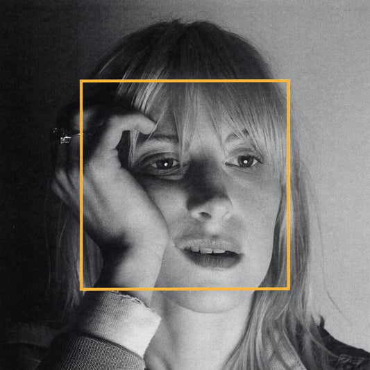 Black and white portrait of Hayley Williams framed by a yellow square.